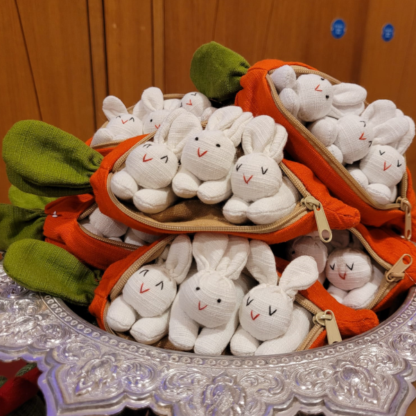 A carrot purse bursting with three bunnies