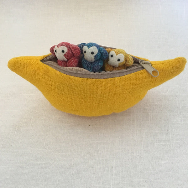 Three cheeky fun loving monkeys who happily live in their banana purse home