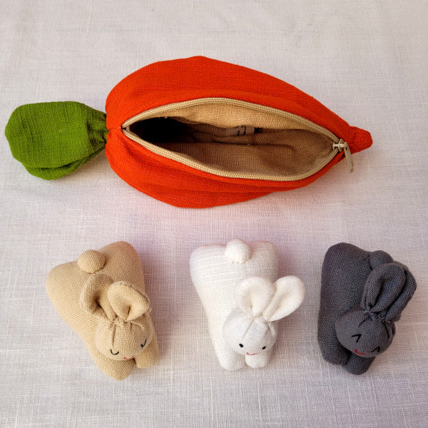 A carrot purse bursting with three multicultural bunnies