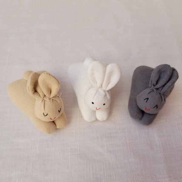 A carrot purse bursting with three multicultural bunnies