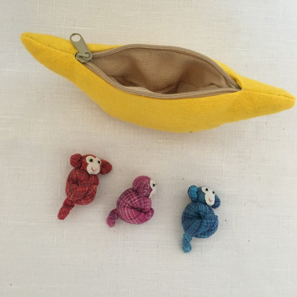 Three cheeky fun loving monkeys who happily live in their banana purse home